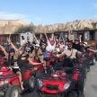 a group of people sitting on atvs with their hands in the air