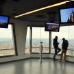 two people standing in a room looking at the view from the cn tower
