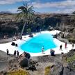 a group of people standing around a swimming pool in a canyon