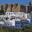 a group of white buildings with a castle in the background