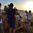 a group of people standing on a mountain watching the sunset