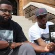 two men sitting on steps holding a book