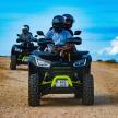 three people riding on atvs on a dirt road
