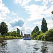 a blue boat traveling down a river with trees