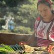 a woman preparing food on a table with vegetables