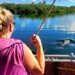 a woman on a boat looking at a dolphin in the water