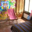 a woman standing next to a pink chair in a room