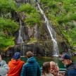 a group of people on a boat in front of a waterfall