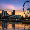 a ferris wheel in front of a city at sunset