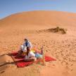 两个人坐在沙漠中的毯子上