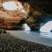 a cave on a beach with a boat in the water