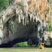a yellow boat in the water in front of a cave