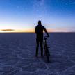 a man standing next to a bike in the desert