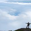 a man standing on top of a mountain with his arms out