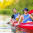 two men and a child in a red kayak on a river