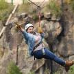 a woman is hanging on a zip line