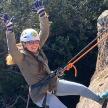 a woman is holding her hands in the air while on a rappelling