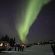 a group of people standing in the snow under the northern lights