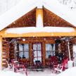 a snow covered cabin with red chairs in the snow
