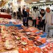 a group of people standing around a market with seafood