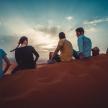 a group of people sitting on the sand in the desert
