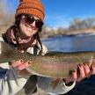 a woman holding a brown trout on a lake