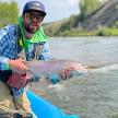 a man holding a fish in a kayak on a river