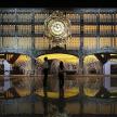 two people are standing in front of a large clock
