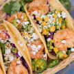 a basket filled with tacos with shrimp and vegetables