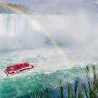 a boat with a rainbow in front of a waterfall