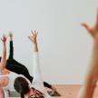 two women in a pilates class with their arms in the air