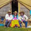 a group of three people sitting in front of a hut