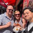 two men and a woman eating food on a street