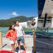a man and a woman standing on a dock next to a plane