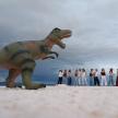 a group of people standing next to a dinosaur statue