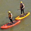two people are standing on kayaks in the water