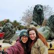 two women posing in front of a fountain with lions