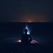 a man sitting on the beach at night