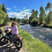 a woman sitting on a motorcycle next to a river