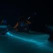 a woman in a kayak in the water at night