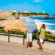 a man and woman standing on a bridge looking at the beach