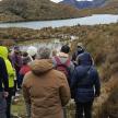 a group of people walking on a trail near a lake