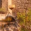 a stone wall with a water fountain next to some plants