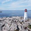 a lighthouse on a rocky shore with a boat in the water