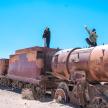 two men standing on top of an old rusty train