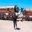 a woman standing in front of austedusted train on the beach