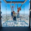 a family jumping on the glass floor of a skyscraper