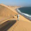 a man walking on a sand dune near the ocean