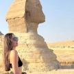 a woman standing in front of the sphinx and pyramid