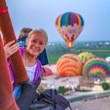 a woman sitting on a bus looking at hot air balloons